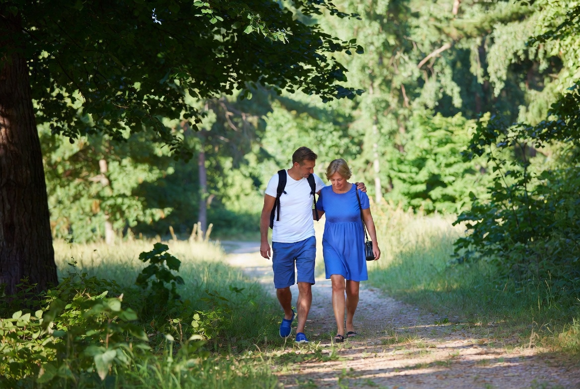 Osoby idące spokojnym krokiem leśną ścieżką